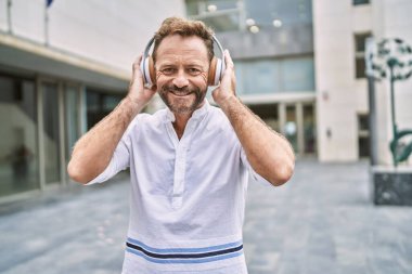 Şehirde müzik dinleyen orta yaşlı bir adam.