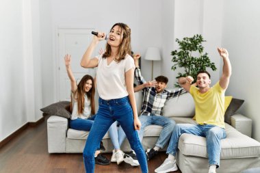 Bir grup genç arkadaş evde mikrofon kullanarak şarkı söylüyor..