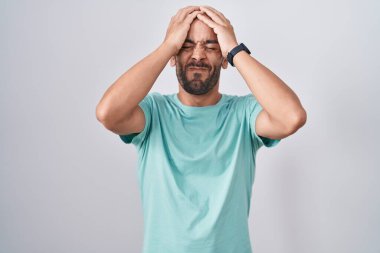 Middle age bald man standing over white background suffering from headache desperate and stressed because pain and migraine. hands on head. 