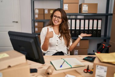 Küçük işletme şirketinde çalışan genç İspanyol kadın avuç içini gösteriyor ve baş parmaklarıyla iyi bir hareket yapıyor, mutlu ve neşeli gülümsüyor. 