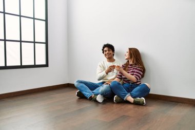 Genç İspanyol çift şampanya ile kadeh kaldırıyor. Yeni evlerinde yerde oturuyorlar..