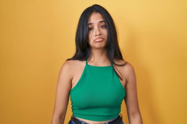 Brunette woman standing over yellow background depressed and worry for distress, crying angry and afraid. sad expression. 
