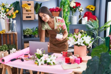 Çiçekçide dizüstü bilgisayar kullanan güzel İspanyol bir çiçekçi.