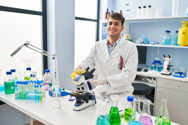 若いヒスパニック系の男科学者笑顔自信を持って洗浄顕微鏡で実験室 — ストック写真