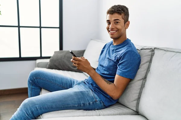 Jovem Hispânico Relaxante Sentado Sofá Usando Smartphone Casa — Fotografia de Stock