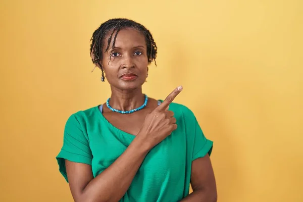 African Woman Dreadlocks Standing Yellow Background Pointing Hand Finger Side — Stockfoto