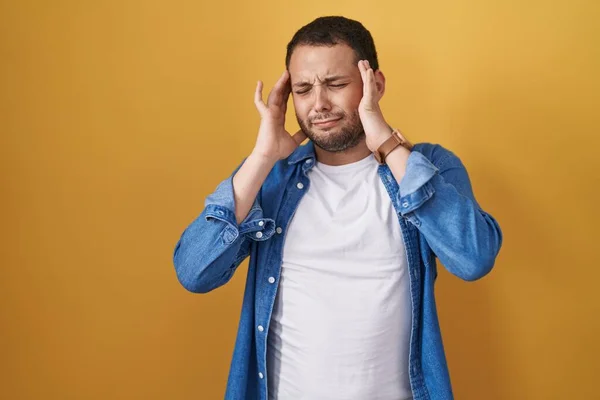 ヒスパニック系の男性の頭の上に手で黄色の背景に立って 頭痛の種のためのストレス 片頭痛 — ストック写真