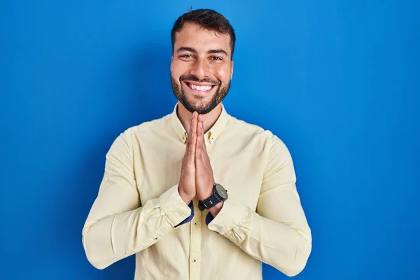 Handsome Hispanic Man Standing Blue Background Praying Hands Together Asking — Stockfoto