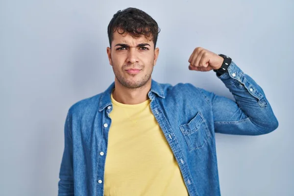 Homem Hispânico Jovem Sobre Fundo Azul Pessoa Forte Mostrando Músculo — Fotografia de Stock