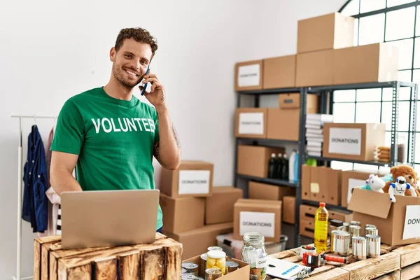 Jonge Spaanse Man Vrijwilligersuniform Gesprek Smartphone Het Liefdadigheidscentrum — Stockfoto