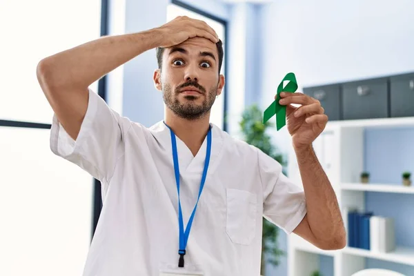 Young Hispanic Doctor Man Holding Support Green Ribbon Clinic Stressed — Stockfoto