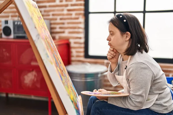 Young woman with down syndrome artist drawing with doubt expression at art studio