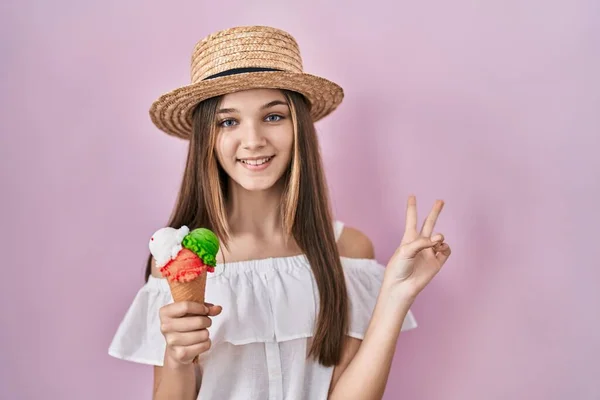 카메라 앞에서 얼굴을 윙크하며 아이스크림을 소녀가 손가락으로 승리의 표시를 — 스톡 사진