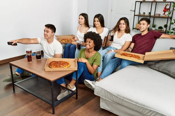 Group of young friends eating italian pizza and watching movie at home.