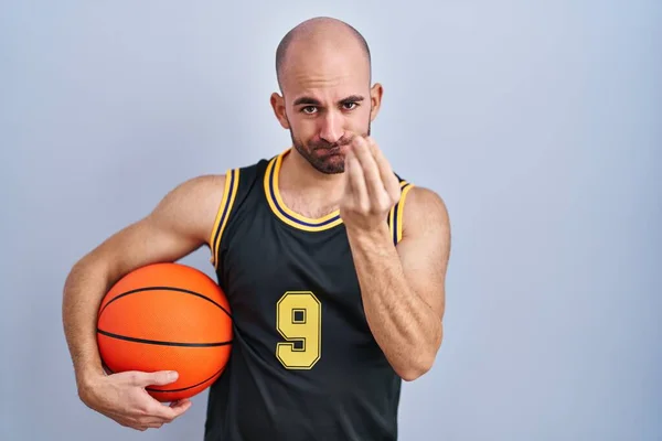 年轻的秃头男子 留着胡子 身穿篮球服 手持球 手指手画脚地做着意大利式的手势 — 图库照片