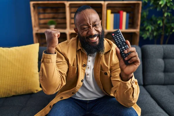 Hombre Afroamericano Sosteniendo Control Remoto Televisión Gritando Orgulloso Celebrando Victoria —  Fotos de Stock