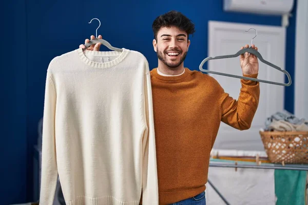 Hispanic Man Med Skägg Håller Tröja Hängare Tvättstuga Firar Galen — Stockfoto