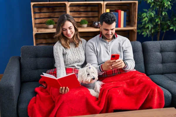 Hombre Mujer Leyendo Libro Usando Smartphone Sentado Sofá Con Perro —  Fotos de Stock