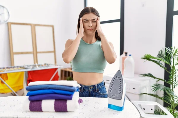 Young Hispanic Woman Ironing Clothes Laundry Room Hand Head Pain — Zdjęcie stockowe