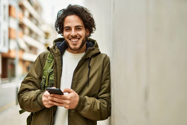 Hombre Hispano Guapo Usando Teléfono Inteligente Apoyado Pared —  Fotos de Stock