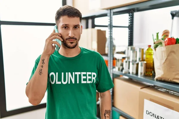 Joven Hombre Hispano Vistiendo Camiseta Voluntaria Hablando Por Teléfono Pensando — Foto de Stock