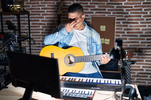 Jovem Hispânico Tocando Guitarra Clássica Estúdio Música Cheirando Algo Fedorento — Fotografia de Stock