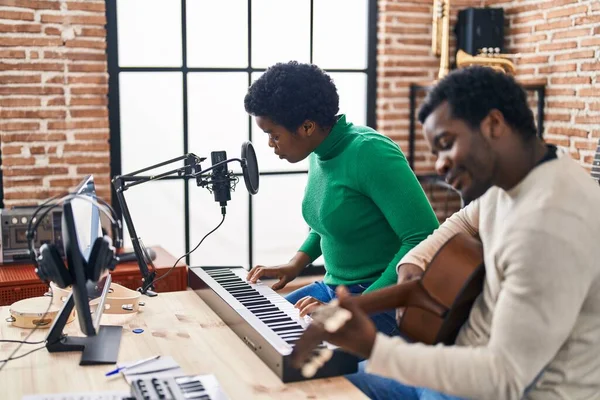 African american man and woman music group singing song playing guitar and piano keyboard at music studio