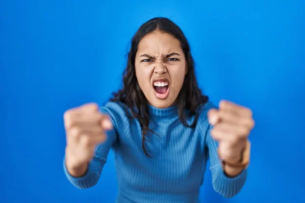青の孤立した背景に立っている若いブラジル人女性は怒りで叫びながら怒りと怒りの拳を上げる怒っていると激怒しました 怒りと攻撃的な考え方 — ストック写真