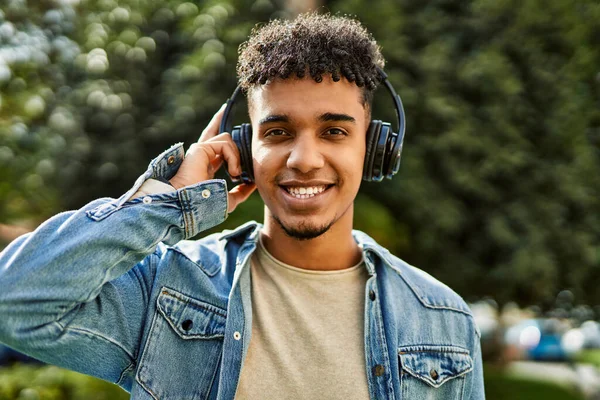 在大学校园里听音乐的西班牙裔年轻人头戴耳机 — 图库照片