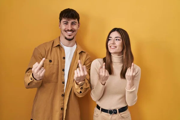 Young Hispanic Couple Standing Yellow Background Showing Middle Finger Doing — стоковое фото