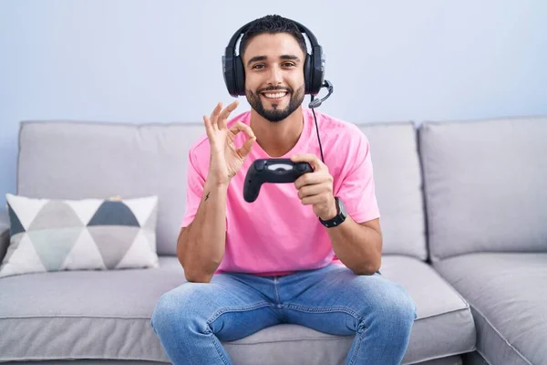 Joven Hispano Jugando Videojuego Sosteniendo Controlador Sentado Sofá Sonriendo Positivo —  Fotos de Stock