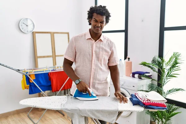 African Man Curly Hair Ironing Clothes Home Winking Looking Camera — Stockfoto