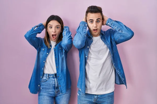 Young Hispanic Couple Standing Pink Background Crazy Scared Hands Head — Stockfoto