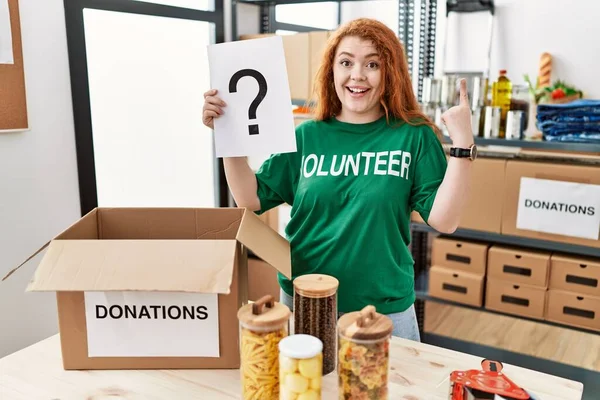 Young Redhead Woman Wearing Volunteer Shirt Holding Question Mark Surprised — Stock Photo, Image