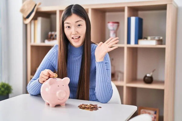 Jovem Chinesa Colocando Moeda Banco Porquinho Comemorando Realização Com Sorriso — Fotografia de Stock