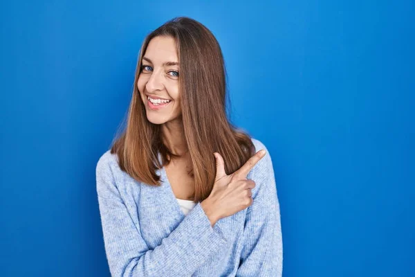 Young Woman Standing Blue Background Cheerful Smile Face Pointing Hand — Stockfoto