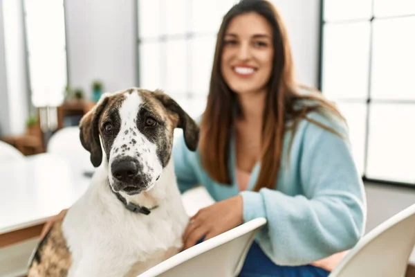 Mujer Joven Sonriendo Confiada Sentada Mesa Con Perro Casa — Foto de Stock