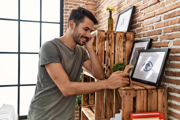 Young Hispanic Man Smiling Confident Looking Picture Frame Home — Zdjęcie stockowe