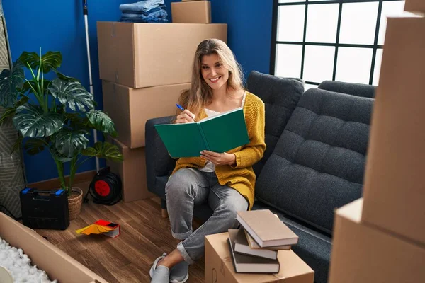 Young Blonde Woman Smiling Confident Writing Book New Home — ストック写真