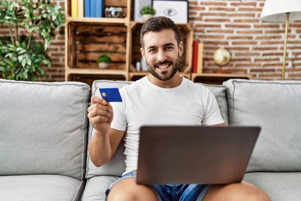 Jonge Spaanse Man Glimlacht Zelfverzekerd Met Laptop Creditcard Thuis — Stockfoto