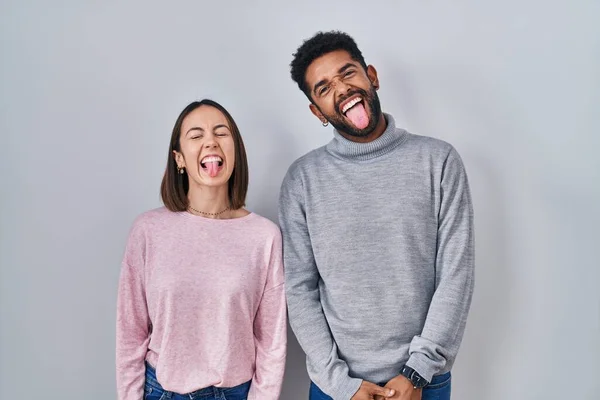 Young Hispanic Couple Standing Together Sticking Tongue Out Happy Funny — Stockfoto