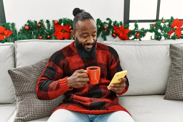 Young African American Man Drinking Coffee Using Smartphone Sitting Christmas — Stock fotografie