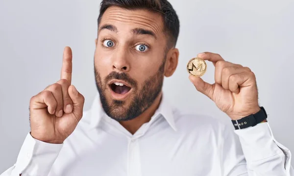 Hombre Hispano Guapo Sosteniendo Moneda Criptomoneda Monero Sorprendido Con Una — Foto de Stock