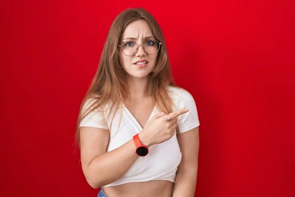 赤の背景の上に立つ若い白人女性が心配し 額で緊張し 心配し 驚きの表情 — ストック写真