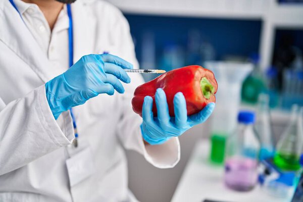 Young hispanic man scientist analysing red pepper at laboratory
