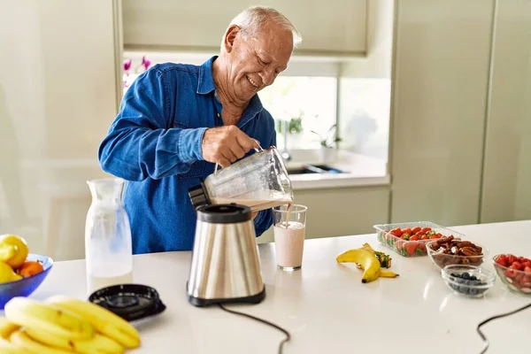 Hombre Mayor Sonriendo Confiado Vertiendo Batido Sobre Vidrio Cocina —  Fotos de Stock