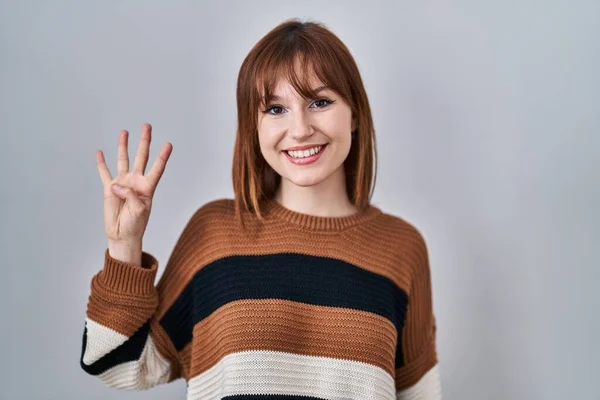 年轻美丽的女人穿着条纹毛衣 披着孤立的背景 带着四号手指 面带微笑 自信而快乐 — 图库照片