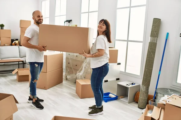 他的年轻夫妇笑着高兴地在新家拿着大纸板箱 — 图库照片