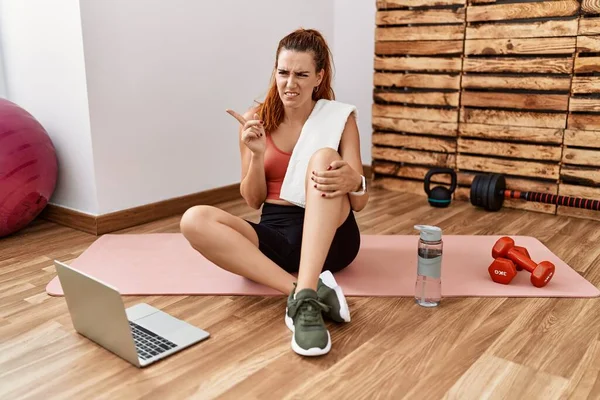 Joven Pelirroja Viendo Tutorial Entrenamiento Gimnasio Señalando Lado Preocupada Nerviosa — Foto de Stock