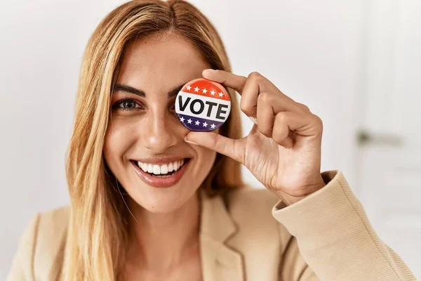 Young american politic party worker holding vote badge over eye at electoral college